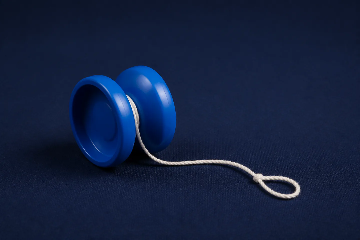 Responsive blue butterfly yo-yo with neatly wound white string beside a second beginner yo-yo on a dark blue floor mat with no hands, people, text or logos